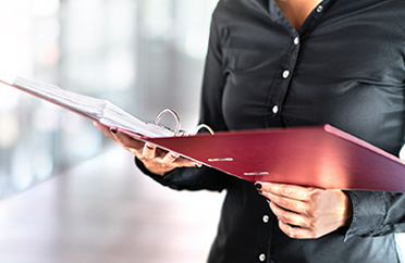 woman holding red binder full of paper