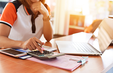 woman typing on a calculator as she reviews cash flow reports